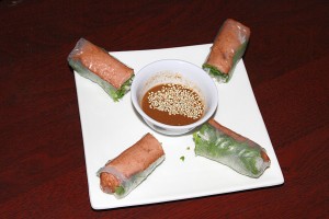 Roses on the Grill Rolls, flavorful and fragrant spring rolls served with a peanut dipping sauce, are prepared with a grilled vegetarian “sausage” instead of the more traditional shrimp.