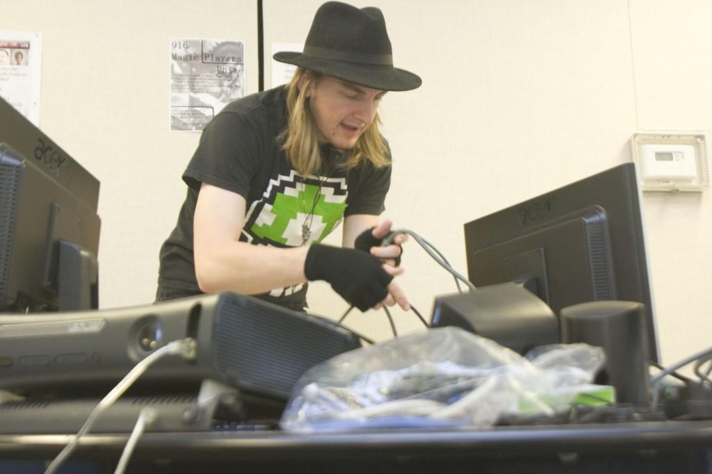 Psychology major Andrew Preston hooks up the wires to connect a PS3 and Xbox 360 console to the back of his computer monitors in the portable cafeteria on Nov. 22, 2011. (Photo by Demetric Good)