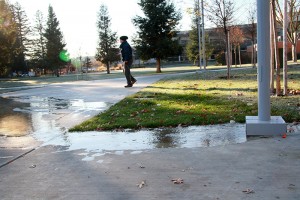 Dawn Benjamin from Los Rios Facilities works to turn off the sprinkler system that malfunctioned, spilling water onto a campus walkway today.