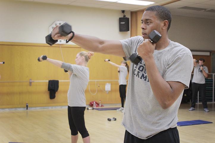 Using two hand weights, Cleveland Braswell executes rotating punches during a three-part circuit workout during the Boot Camp Fitness class at American River College. (Photo by Emily K. Rabasto)
