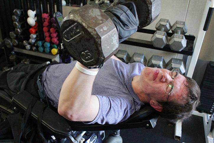 American River College student Adam Felton, 22, lifts a 25-pound dumbbell while in the reclined position of his electric wheelchair during his adaptive P.E. class. (Photo by Emily K. Rabasto)