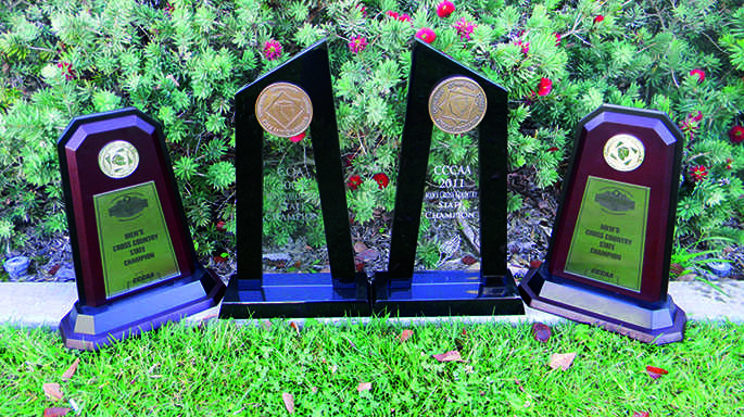 The men’s cross country team’s first place state championship awards from 2013, 2012, 2011, and 2005.