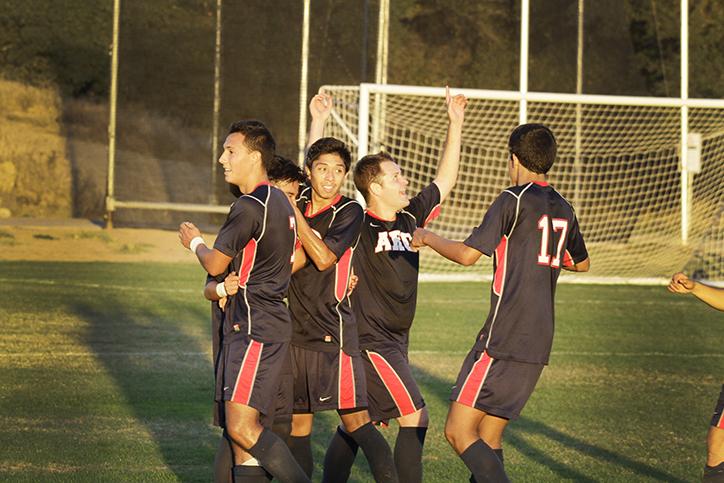 The men’s soccer team celebrates after scoring the only point of the game, which resulted in their first win of the season.