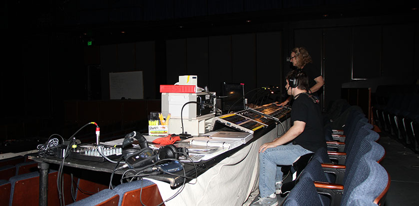 Sound and light workers at the rehearsal for the theatre production Blues for Mr. Charlie, Kathy Burleson professor in the theatre arts department standing up and an American River student sitting down taking cues from Burleson.