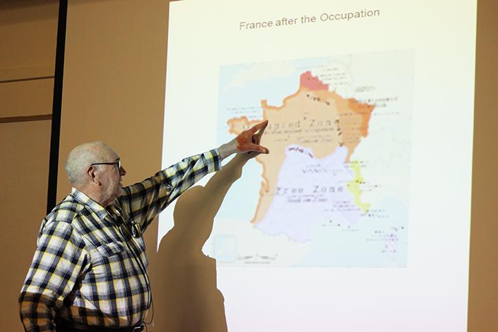 Conrad Tracy, husband of Holocaust survivor Renee Heck, shows the audience the approximate location of where Heck and her mother escaped to in France when they left their home in Germany. Tracy shared the story of his wife, who had passed last spring, during an event that remembered survivors of the Holocaust.