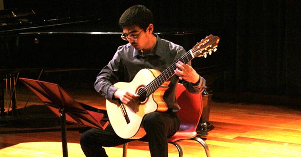 American River College student, Eric Kuvakos strums the guitar to the musical piece, titled Round Midnight during last Fridays music recital.