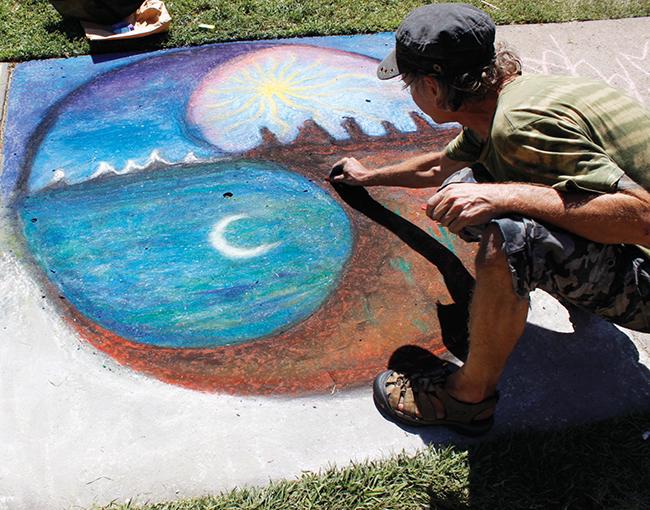 John Steensland, a former American River College student, adds finishing touches to his  chalk-drawing for Chalk It Up. He said he liked the way the texture of his art looked on the pavement. (Photo by Cheyenne Drury)