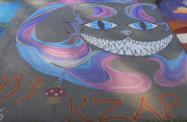 An advertisement for the radio station 99.3 “KZAP” at Chalk It Ups 25th annual art festival on Labor day weekend in Fremont park, downtown Sacramento. The chalk art appears to be a depiction of the cheshire cat from the film “Alice in Wonderland”. (Photo by Cheyenne Drury)