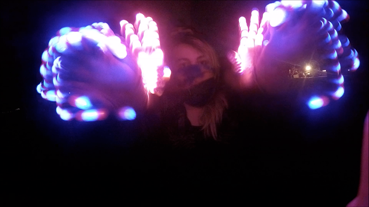 This screenshot shows American River College students Anthony Perez and Vanessa Lamb perform a light show with gloves that are outfitted with LED lights. This type of performance has been associated with the electronic dance music scene. (Image capture of a video by Lena DoBynes)