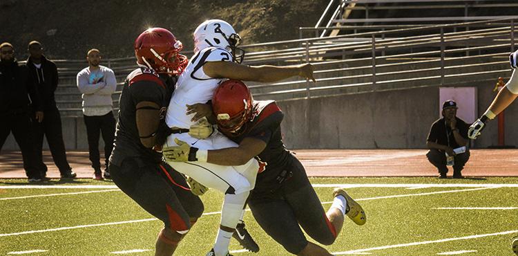 American River College’s quarterback Jihad Vercher getting tackled by Community College of San Francisco players Rod Jones and Austin Larkin during a game at CCSF on Sept. 26, 2015. (Photo by Ashlynn Johnson)