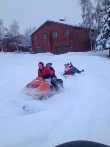 American River College volleyball outside hitter Nora Troppmann rides a snow machine with her friend and drags her siblings on a sled tied to the machine. Troppmann said this was one of her favorite activities to take part in while living in Alaska. (Photo courtesy of Nora Troppmann)