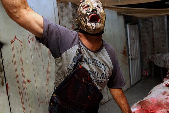 Jason Becker, a cast member of Slipknots Scream Park warms up moments before the doors opens to the public. His costume was inspired by the outfit of Corey Taylor, the lead singer of the American rock band Slipknot. (Photo by Joseph Daniels)