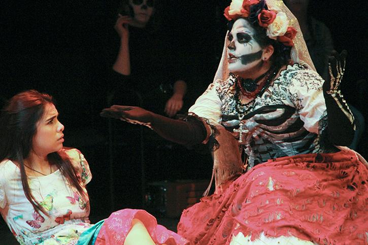 Maya (played by McKenzie Lopez), left is visited by Santa Muerte (played by Itzin Alpizar) after praying that her dead mothers soul is left restless. The play will run until Dec. 6. (Photo by Joseph Daniels)