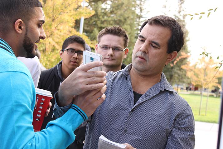 ARC student Nate Ihsan uses his phone to show a verse in the Quran denouncing killing to anti-Muslim activist Vincent Bradshaw, who erected a sign reading Why Islam Kills in front of the Student Center on Tuesday. (Photo by Barbara Harvey)