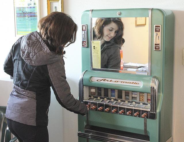 Abbey Cocreham demonstrates use of the Art-O-Matic art dispenser at the Kaneko Gallery at American River College in Sacramento, California on Feb. 18. The Art-O-Matic reopened this semester to raise money for the gallery. (Photo by Hannah Darden)