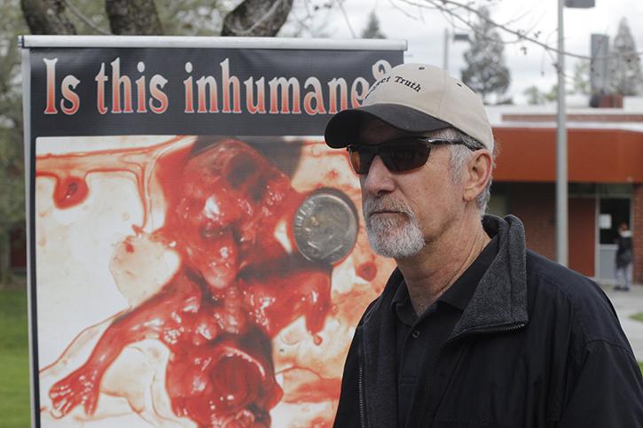 John Edgar, a member of the anti-abortion activist group Project Truth, stands in front of one of the groups signs posted by its set up near the Student Center. Project Truth visits college campuses among other venues across the country to spread its message. (File Photo)