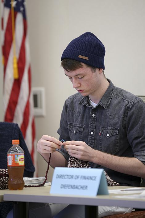 CAEB president Justin Nicholson knits during a student senate meeting on Feb. 25.  (Photo by Kyle Elsasser)