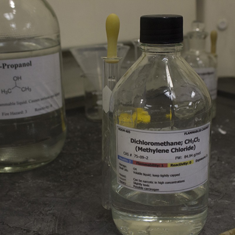 A container of dichloromethane sits ready in the fumehood. It was used to collect the aromatic compounds from the food items in the CHEM 420 organic chemistry course. (Photo by Timothy Lipuma)