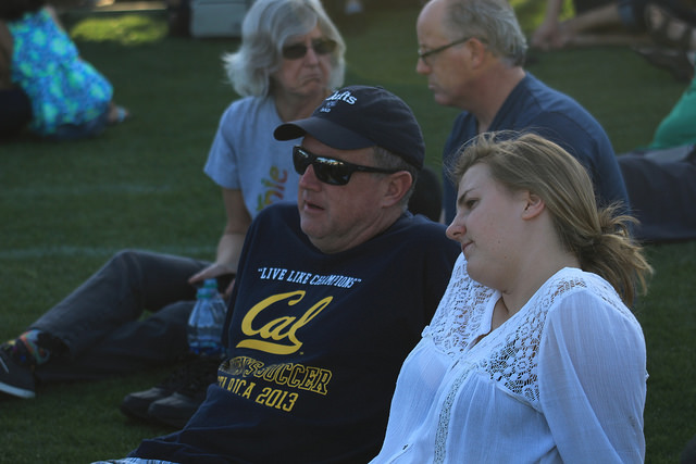 Kevin Bell (left) and Brigid Bell (right) sit on Bonney field at Cal Expo waiting for Bernie Sanders to give his speech at his A Future to Believe In rally on May 9, 2016. Brigid is a first time voter who hopes her undecided father chooses Sanders.(Photo by Robert Hansen)