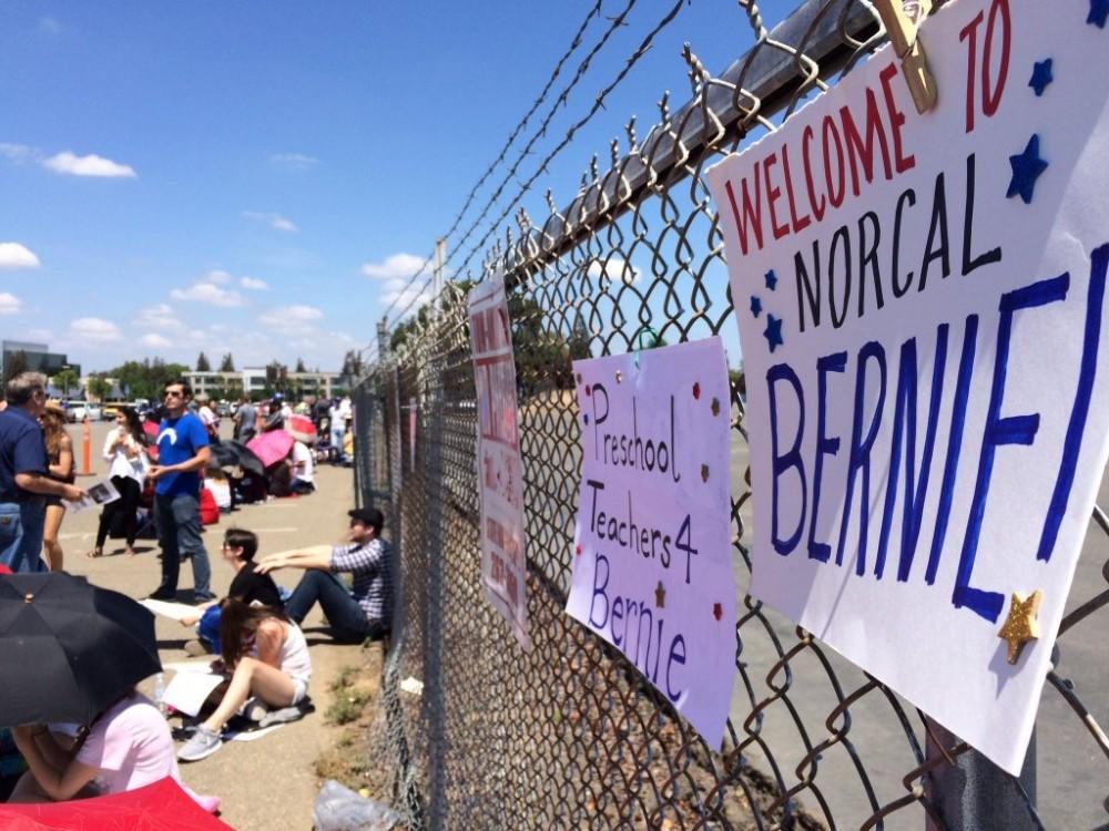 One of the many signs brought to the Sacramento Bernie Sanders rally hangs along a fence in front of the line forming at Bonney Field in Cal Expo. The line started forming around 8 a.m. and the doors open at 5 p.m. (Photo by Hannah Darden)