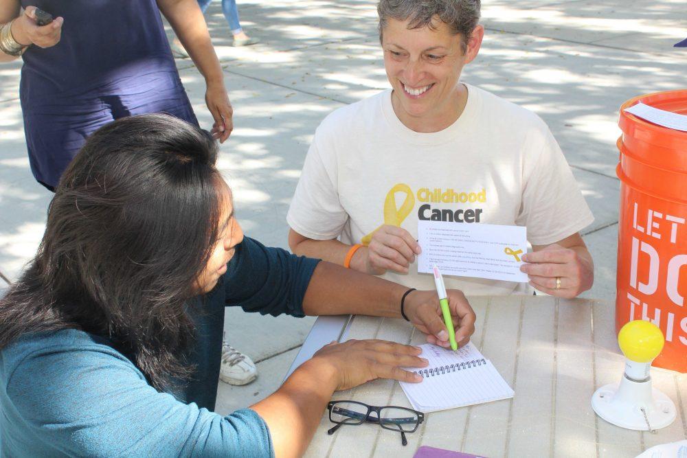 Renee Marie watches American River College student Omar Ramirez sign an encouraging mesage to her nephew Xander, who now shows no signs of cancer. (Photo by Robert Hansen)