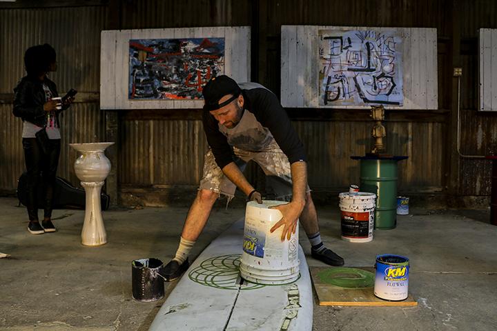 Artist John Klaiber paints the flower of life geometric design on an old surfboard during his Zoo Time solo exhibition on Nov. 12. (Photo by Luis Gael Jimenez)