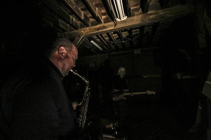 Band leader Tony Passarell playing saxophone towards in almost total darkness during a performance at the Panama Art Factory on Nov. 12. (Photo by Luis Gael Jimenez)