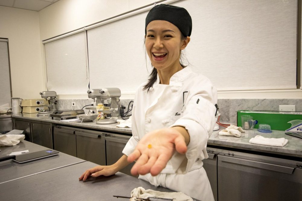 Head chef Lisa Lam Chiao holds a piece of candied orange peel as she prepares to make orange hazlenut chocolate bark. Chiao prepared the orange slices in her own home the night before. (Photo by Ashley Hayes-Stone)