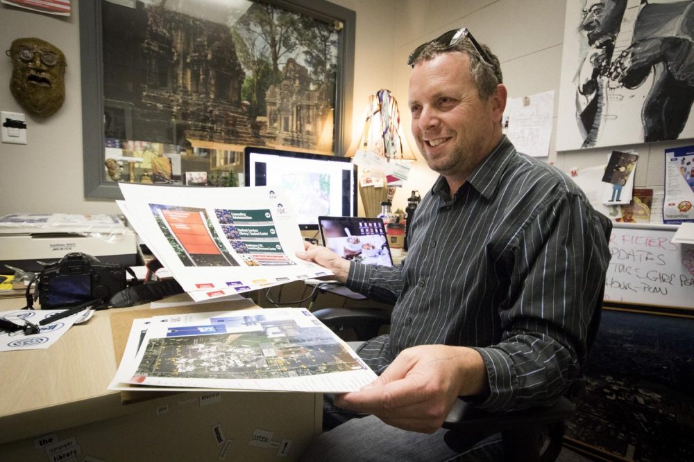 American River College Printing Services Supervisor Don Reid holds up a prototype for the new campus maps that he is working on. (Photo by Ashley Hayes-Stone)