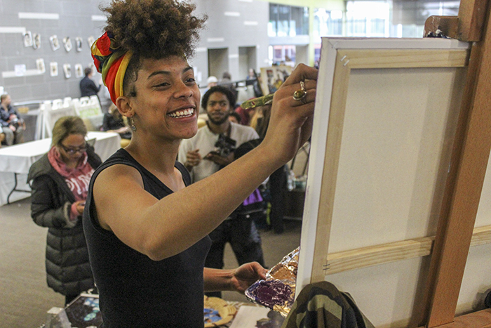 Artist Aliyah Sidqe stood above a crowd of onlookers as she spent two hours painting live during American River College’s Black Heritage Celebration on Feb. 22.  (Photo by Jennah Booth)