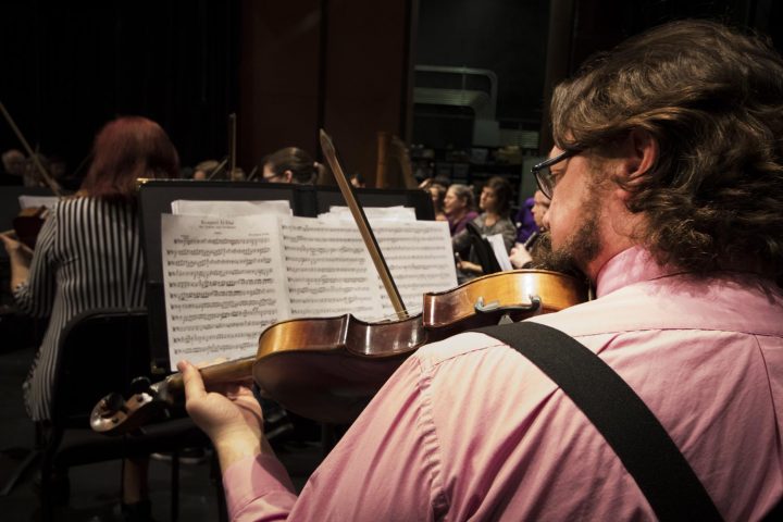 John Hering looks at his sheet music as he plays his violin during the American River College Orchestra’s rehearsal on Mar. 8 at American River College.(Photo by Ashley Hayes-Stone)
