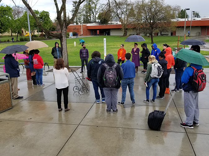 American River College students and faculty gather around a makeshift vigil in front of the library on March 14. They walked out of class and held 17 minutes of silenece in honor of the Parkland High School shooting victims. (photo by Mack Ervin III)