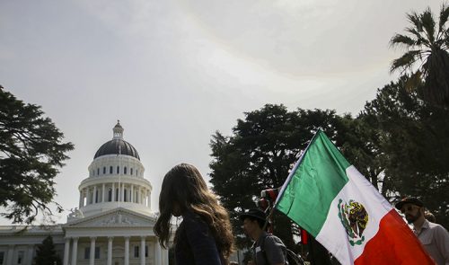 Protesters carry a Mexican flag outside of the California State Capitol on March 31, 2018.