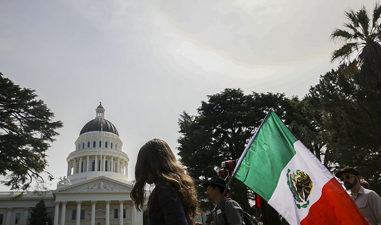 Protesters carry a Mexican flag outside of the California State Capitol on March 31, 2018.