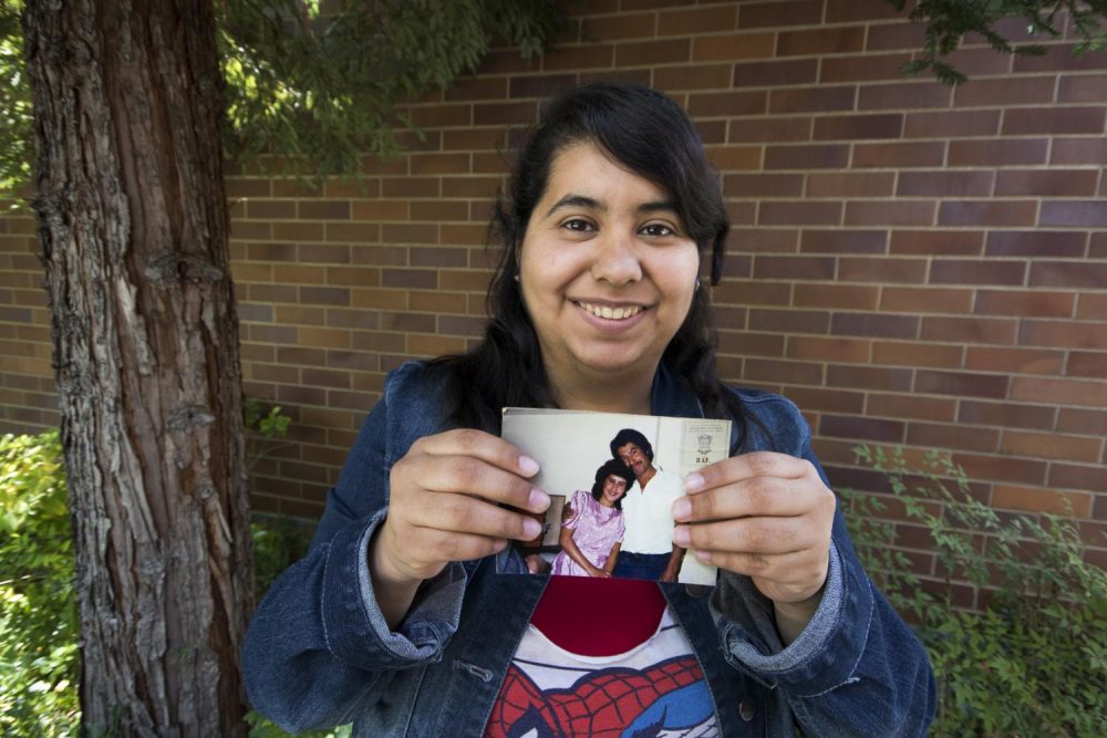 Staff writer Cecilia Castillo Juarez holds a 1988-era photo of her parents in their home of Mexico. (photo by Ashley Hayes-Stone)