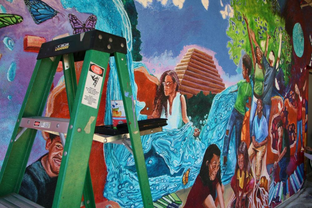 A mural being painted outside of the Learning Resource Center features the likeness of students and symbols that represent Sacramento and American River College on Sept. 1 2018. (Photo by Jennah Booth)