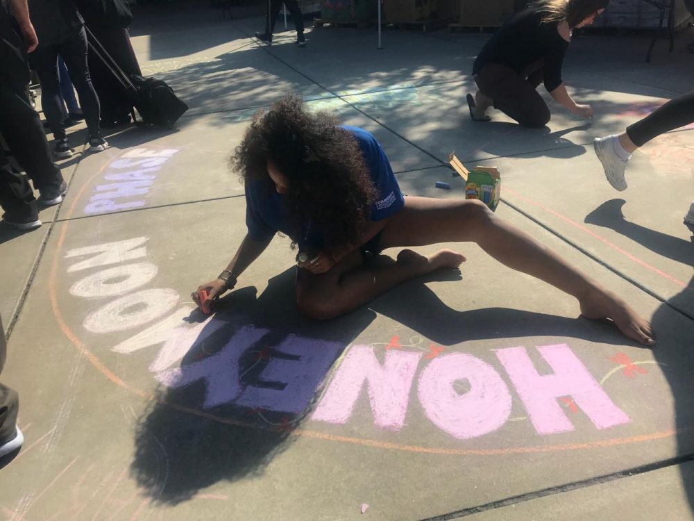 UNITE student Dronme Davis contributes to WEAVEs cycle of violence chalk art in front of the gym at American River College on Oct. 10, 2018. (Photo by Alexis Warren)