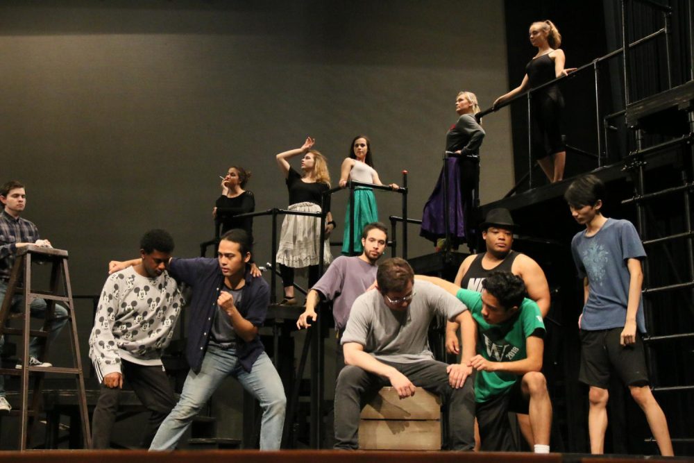 The cast of West Side Story pose on stage, some students atop various stage props, during rehearsals on Oct. 4, 2018. (Photo by  Itzin Alpizar)