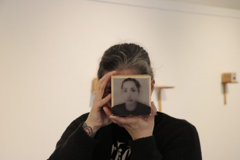 Photographer Angela Casagrande displays her exhibition, “Everything will Disappear,” at the James Kaneko Gallery at American River College on Nov. 28, 2018. Casagrande holds up a box with a picture of her on it. The box contains pieces of her hair because she said making these boxes caused her a lot of stress and made her lose hair. “Everything will Disappear” will run at the Kaneko Gallery until Dec. 14. (Photo by Gabe Carlos)