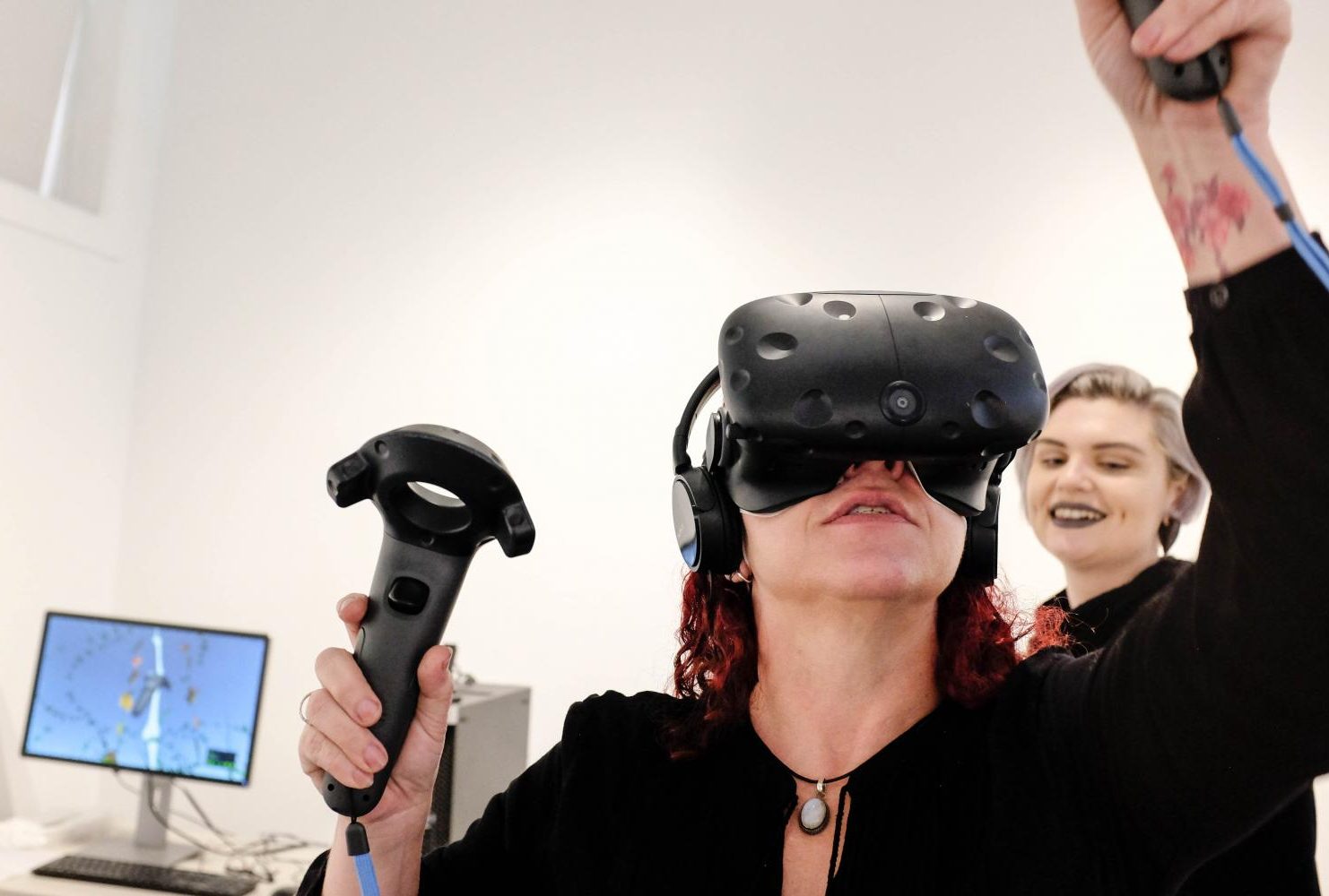 Frankie Vanity, a gallery intern, demonstrates a Virtual Reality segment of Ecotones, an interactive exhibit in the James Kaneko Gallery by artist Rachel Clarke. Gallery intern Jade Jacobs assists in the background on Jan. 28, 2019. (Photo by Patrick Hyun Wilson)