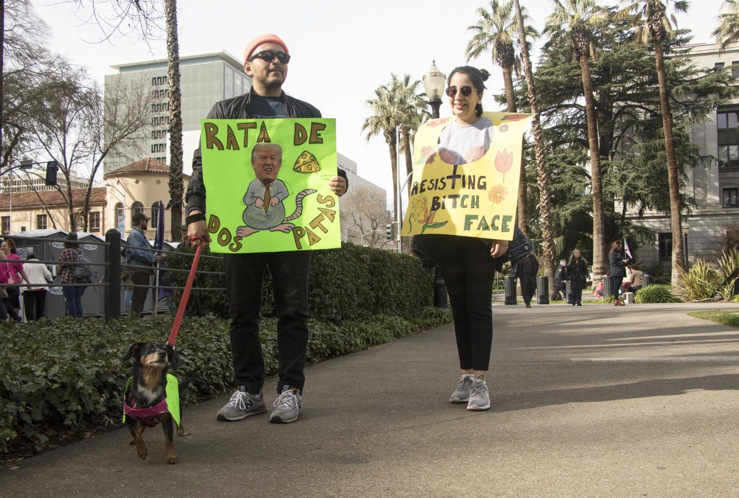 A demonstrator holds a sign that reads “Rata De Dos Patas” which translates to two legged rat as another participant wears her sign that reads “Resisting Bitch Face” at the California State Capitol during the third annual Women’s March.