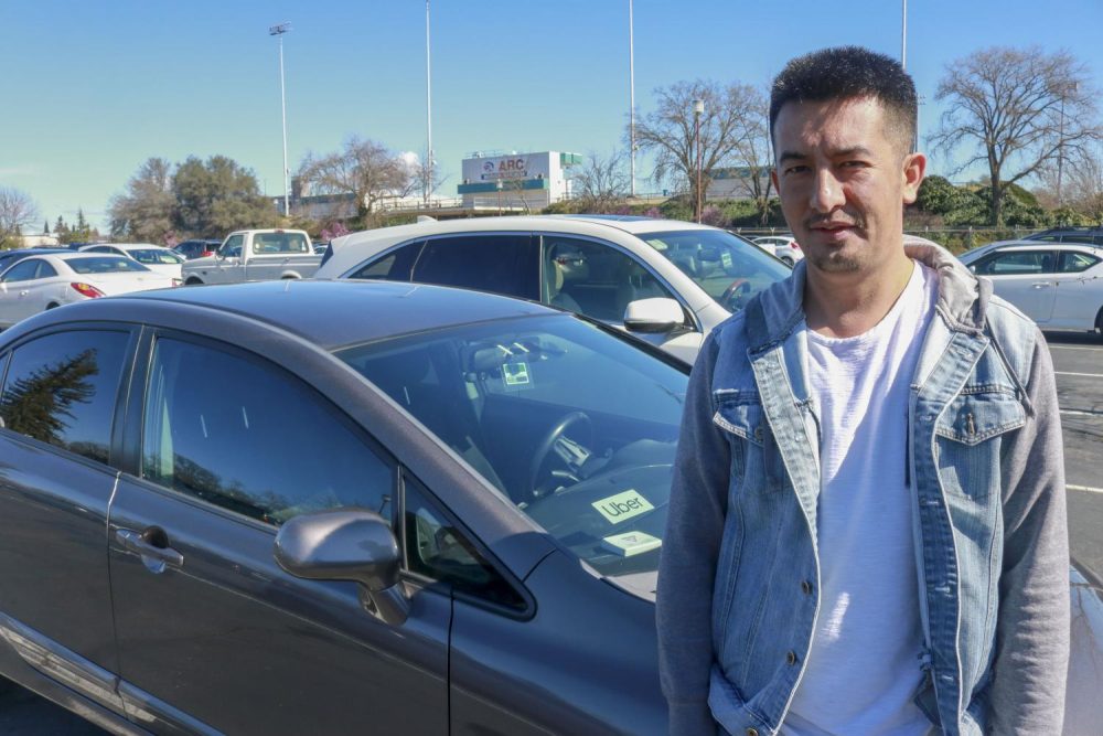 Zabihullah Hashimi poses in front of his car he drives for Uber in a parking lot at American River College on Feb. 20, 2019. Hashimi is a computer science major who is a full-time student at ARC. (Photo By Hameed Zargry)