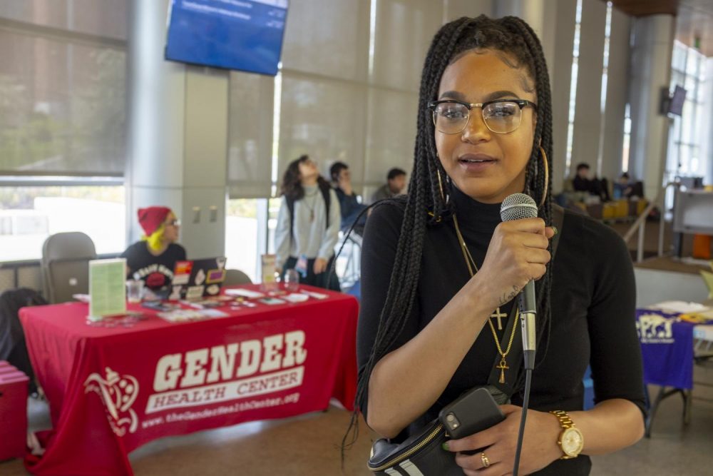 UNITE member Grace Swint, a political science and sociology double major, stands in front of booths for the week-long Womxn’s Health Resource Fair in the Student Center at American River College on March 26, 2019. She, along with other UNITE members, helped organize the event which was combined with their bi-weekly Tell It Tuesday open mic. (Photo by Patrick Hyun Wilson)