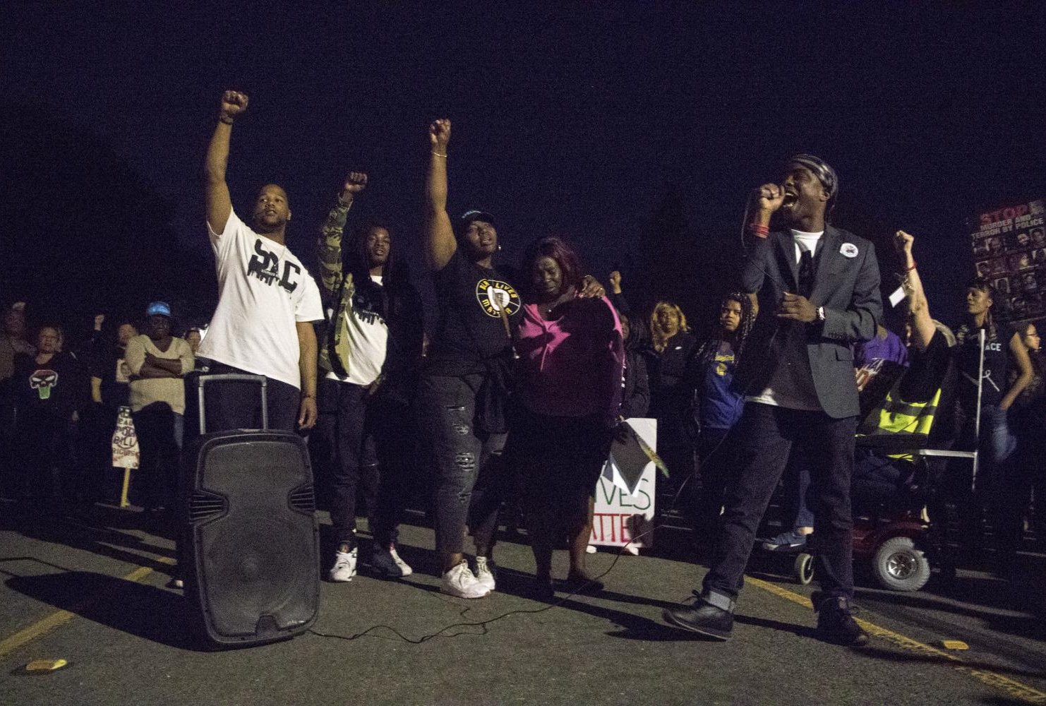tephon Clark’s brother Stevante Clark speaks into a microphone to a crowd of Black Lives Matter Sacramento demonstrators as members of the Clark family raise their fists in the background during the one year anniversary of Stephon Clark’s death in South Sacramento, Calif. on March 18, 2019. (Photo by Ashley Hayes-Stone)