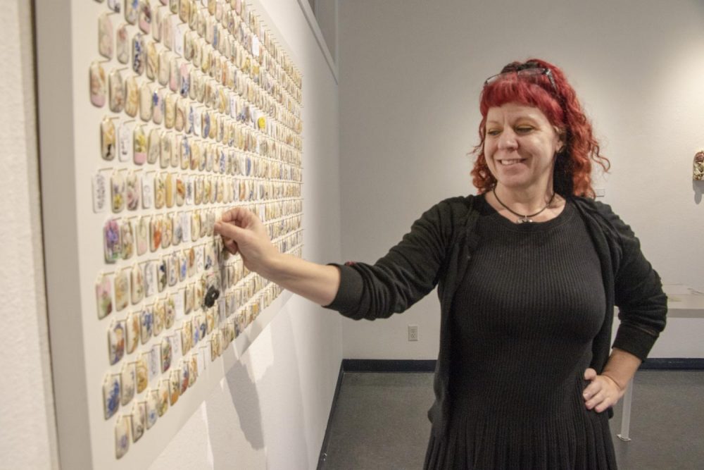 Art major Frankie Vanity gazes at the porcelain tags that hang on the Kaneko Gallery wall at American River College on March 25, 2019. The porcelain tags are a part of artist Shenny Cruces’ exhibition “Managerie,” where students choose and replace with their own art. (Photo by Ashley Hayes-Stone)