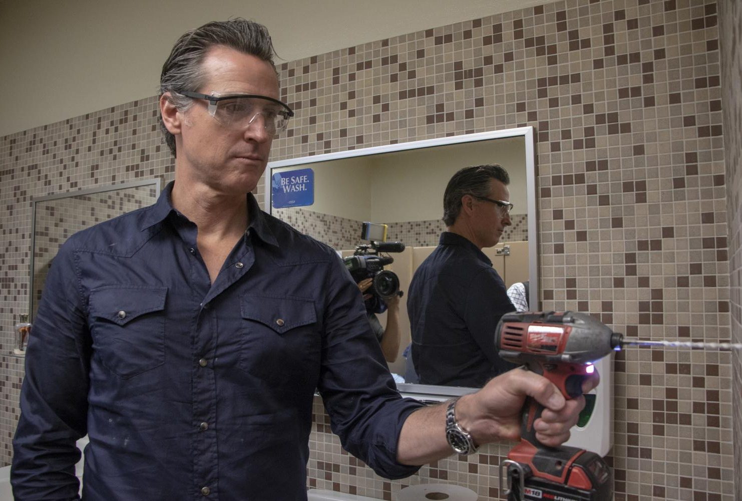 Governor Gavin Newsom assist Maria Arambula with replacing the paper towel dispenser at American River College during International Workers’ Day on May 1, 2019. (Photo by Ashley Hayes-Stone)