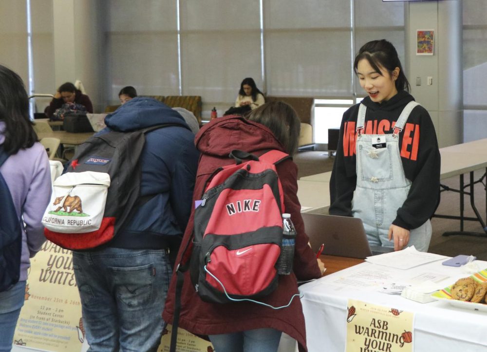 Fang Liu, an economics major and ASB Senator, helps students get warm clothes and first aid kits it the Student Center at American River College on Nov. 26, 2019. (Photo by Joshua Ghiorso)