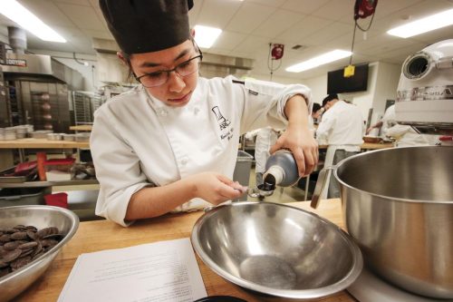 Noemi Cortes Bernal, culinary arts major, measured a teaspoon of chocolate syrup to begin the process of baking a two tone chocolate buttercream cake on Feb.11, 2020. 