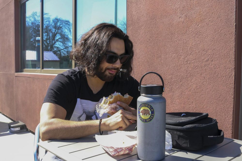Ecology major Josh Moreno enjoys a salami sandwich outside American River College’s Oak Cafe Bakery on Feb. 26 , 2020.(Photo by Brandon Zamora)
