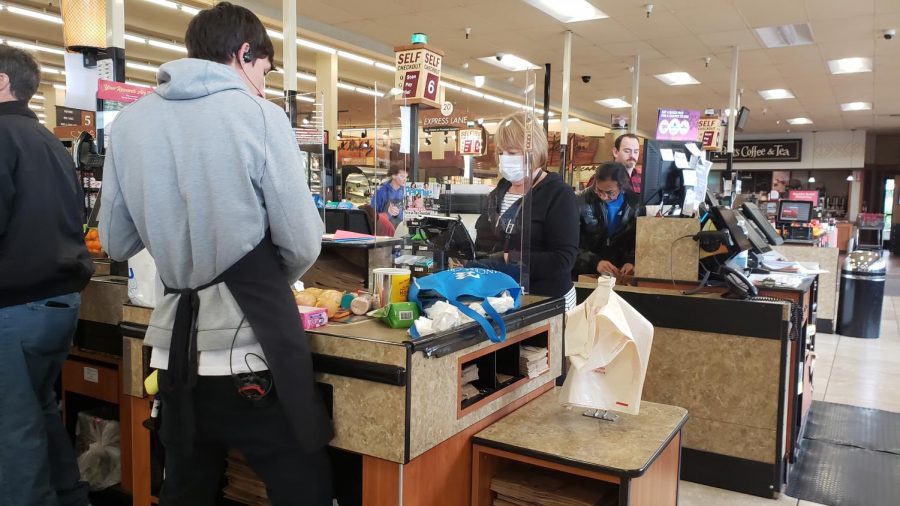 A grocery worker checks out a customer at a Raleys in Carmichael, Calif. on March 20, 2020. With residents in Sacramento living under quarantine, only essential businesses like Raleys Supermarkets are open while taking protective measures. (Photo by Ashley Hayes-Stone)